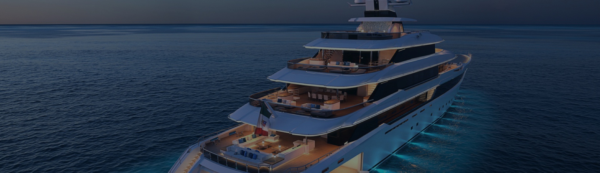 Superyacht moored up at night with lights reflecting on sea.